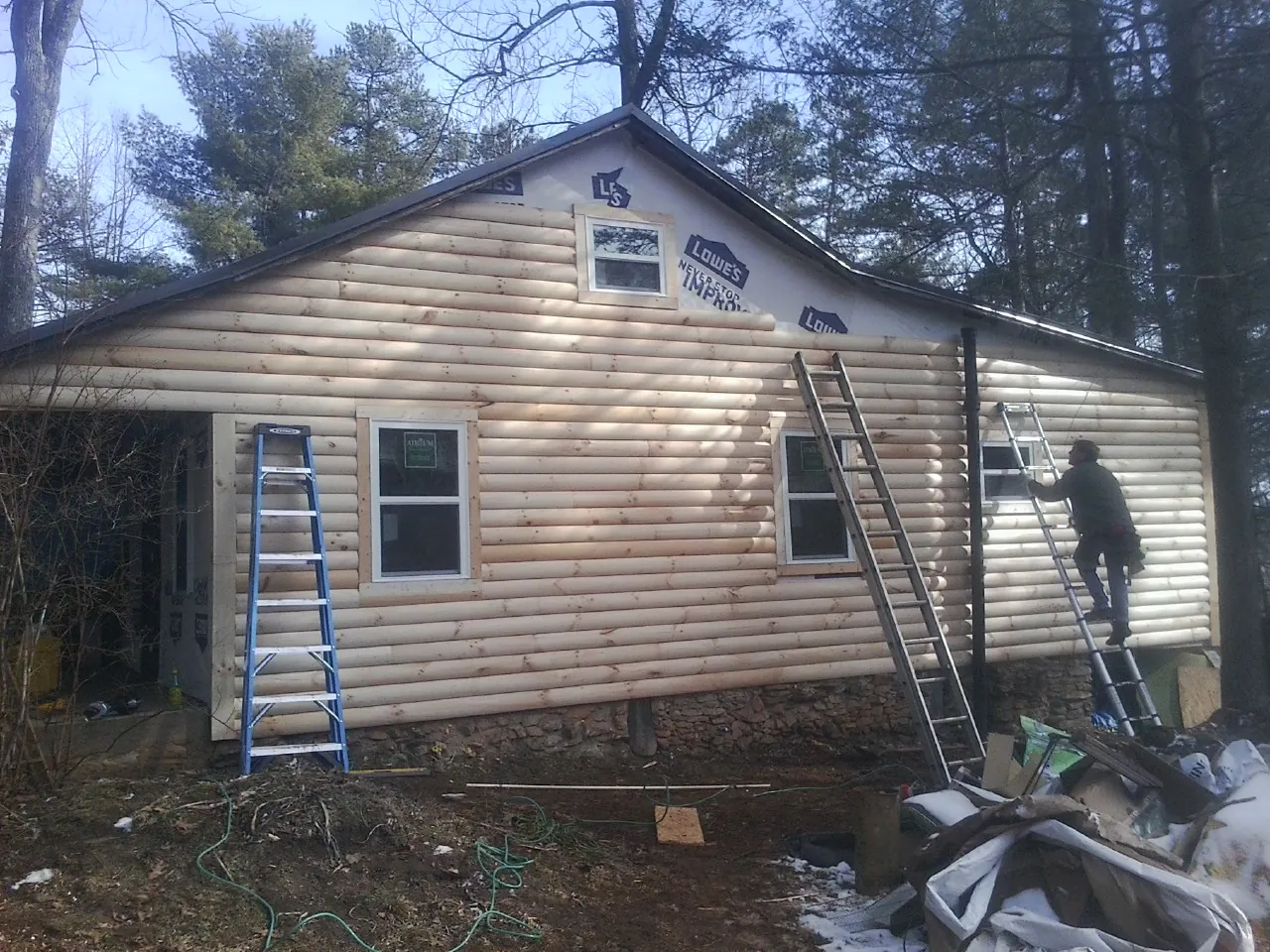 Ladders set against fresh log siding during an exterior remodel in New Hartford