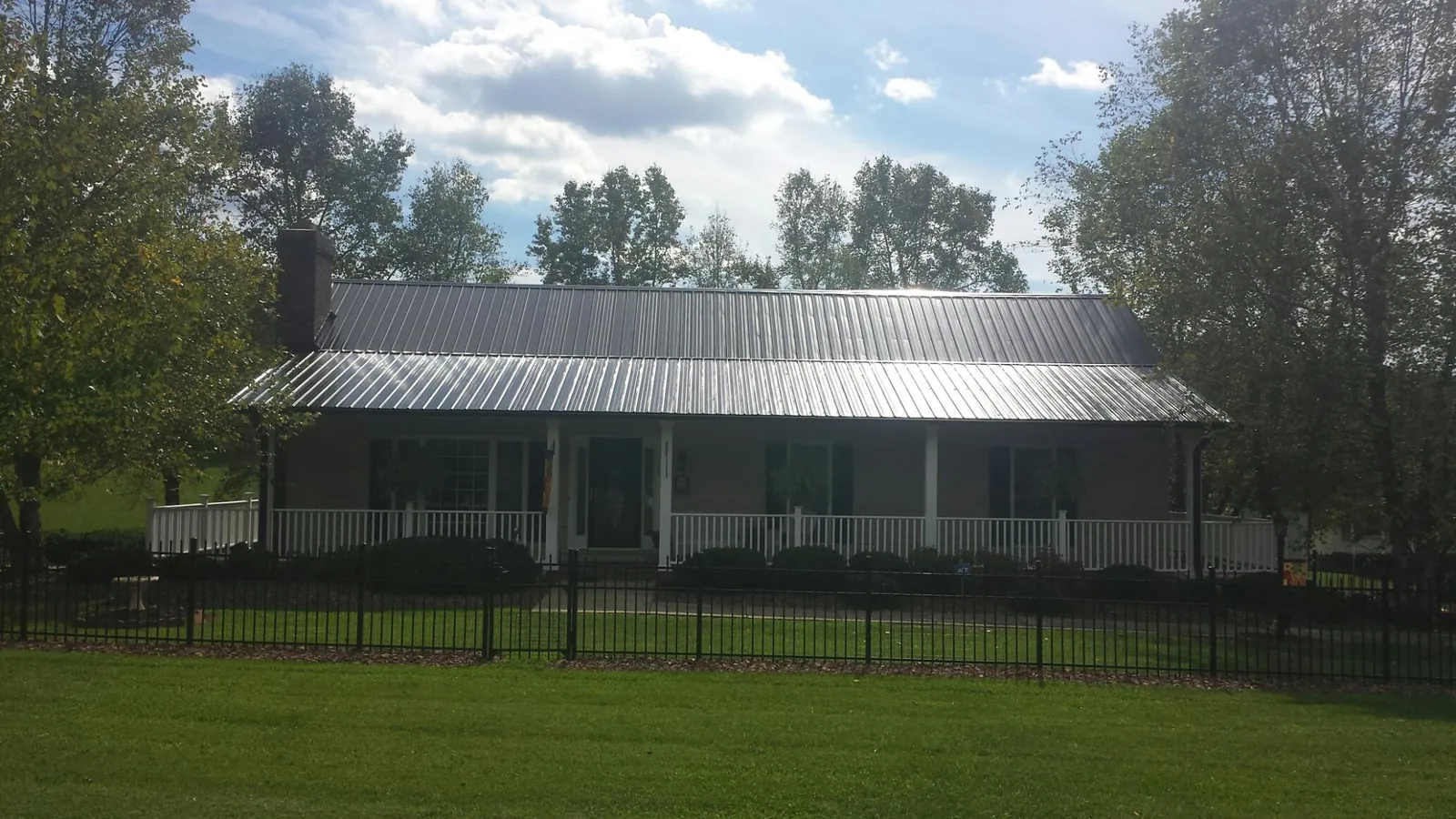 Gray metal roof on a brick ranch with a full width front porch — Gutter Guard Installation work by our crew in New Hartford